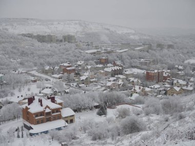 Karla kaplı şehir ve ufuktaki şehir evleri kışın bulutlu olur..