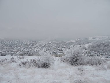 Karla kaplı şehir ve ufuktaki şehir evleri kışın bulutlu olur..