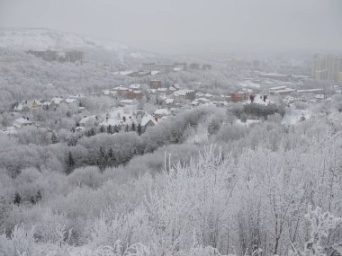 Karla kaplı şehir ve ufuktaki şehir evleri kışın bulutlu olur..