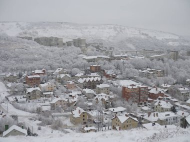 Ufukta karla kaplı şehir ve kentsel evler görünüyor..