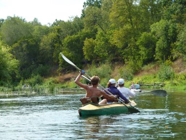 Güneşli bir günde bir grup turist kano üzerinde nehirde rafting yapıyor.
