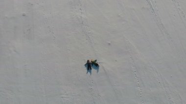 İki çocuk, haç şeklinde taze kar üzerinde yatan kar meleklerini tasvir ediyor. Mutlu ve enerjik, kar damlalarıyla.