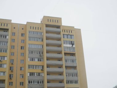 Yüksek binaların balkon yalıtımı için iplere asılan dağcı işçisi..