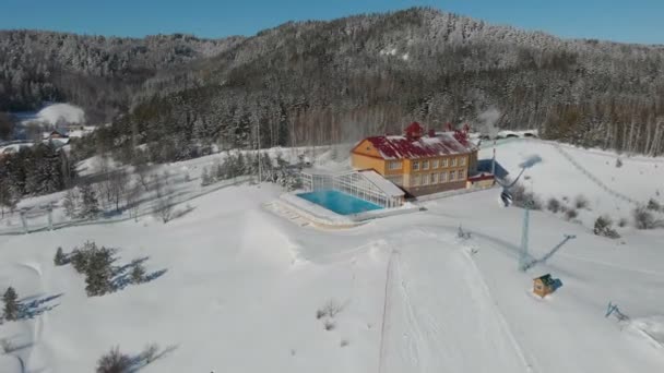 山の真ん中にある豪華な高級ホテルとスパリゾートの空中ドローンショットは、素晴らしいスイミングプールや蒸し水とホットタブで冬の雪に覆われ、スキー後にリラックスします — ストック動画