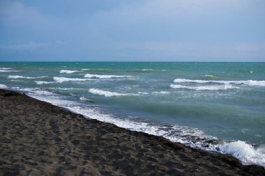 Okyanustan gelen dalgalar kıyıda beyaz kuzular ve köpük oluşturan köpük ve köpüğü görüyor. Kapatın..