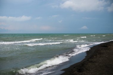 Denizde güzel dalgalar ve siyah kumlar.
