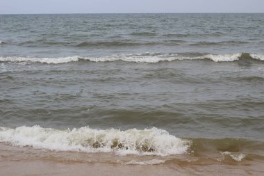 Gün batımında deniz kıyısında dalgalar serpiştiriyor..