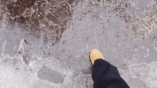 Жіночі ноги в білих черевиках ретельно ходять по слизькій дорозі з замерзлою калюжею, вкритою льодом. Концепція небезпеки — стокове відео