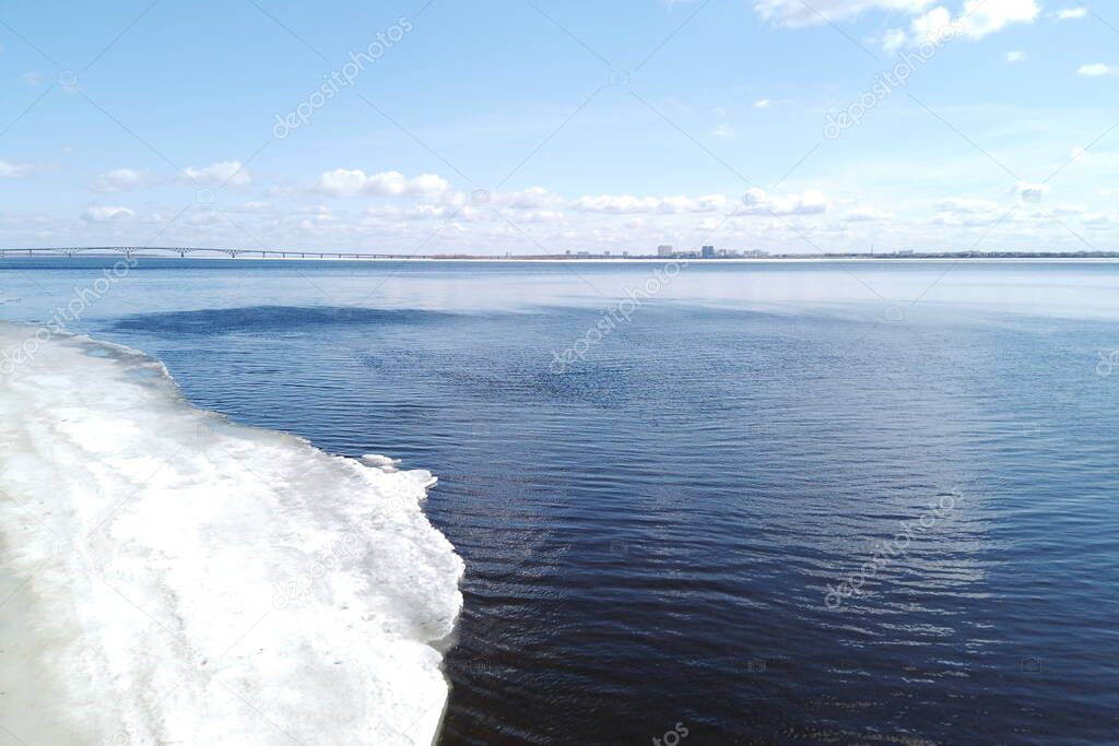 Road bridge over the Volga river between Saratov and Engels, Russia. Ice drift on the river in spring. Embankment in the city of Saratov. Sunny day in April