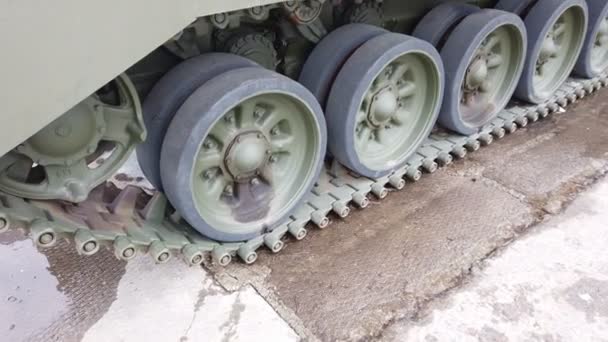 坦克车轮的特写。重型军用坦克的铁轨铁制毛毛虫和军用重型坦克的轮子站在地面上的坦克绿色毛虫前部的视图. — 图库视频影像