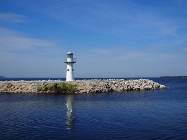 Beyaz yıkanmış deniz feneri derin mavi okyanusa bakıyor..