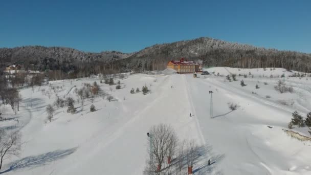 Naturskön dal av hilghland alpina fjällvinter resort på ljusa soliga dag. Vintersport scen med människor njuta av skidåkning och snowboard på preparerade pisets. panoramautsikt över nedförsbackar — Stockvideo