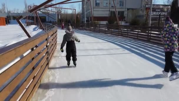 Rusya, Engels - Mart 2021: halka açık buz pateni pisti. Çocuklar ve aileleri buz pateni pistinde geziyorlar. — Stok video