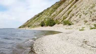 Güneşli bir havada yüksek, kayalık ve sarp bir nehir kıyısına sahip yaz manzarası.