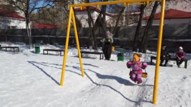 Saratov, Rusya, Mart 2021: İki çocuk, kışın parkta salıncakta salıncakta sallanıyor.