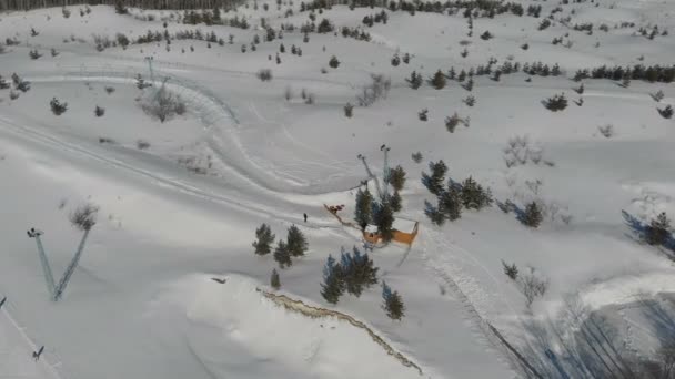 明るい晴れた日に高原の高山の山の冬のリゾート地の風景谷 圧雪のピセットでスキーやスノーボードを楽しむウィンタースポーツシーン 下り坂のパノラマの広い眺め — ストック動画