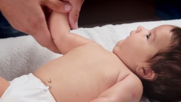 Erkek doktorlar bebeğe el masajı yapar. Masaj yapılan bir çocuk kanepede yatıyor. Bir çocuğun hayatındaki ilk masaj.. — Stok video