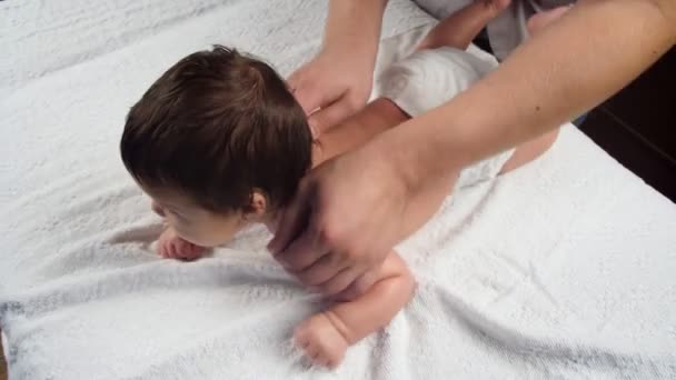 I medici maschi massaggiano il bambino. Un bambino che viene massaggiato è sdraiato sul divano. Il primo massaggio in una vita di bambini. La vista dall'alto. — Video Stock