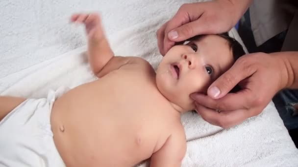Il massaggiatore fa un massaggio al bambino. Un bambino che viene massaggiato è sdraiato sul divano. Massaggio per bambini che alleviano il tono. La vista dall'alto. — Video Stock