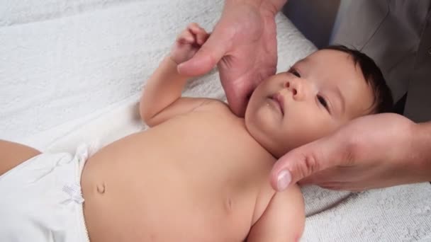 Il massaggiatore fa un massaggio al bambino. Un bambino che viene massaggiato è sdraiato sul divano. Bambino in mutandina. Il primo massaggio in una vita di bambini. La vista dall'alto. — Video Stock