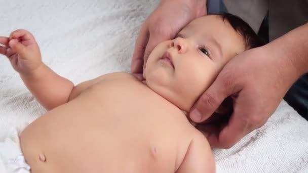 I medici maschi massaggiano il bambino. Un bambino che viene massaggiato è sdraiato sul divano. Il primo massaggio in una vita di bambini. Da vicino. — Video Stock