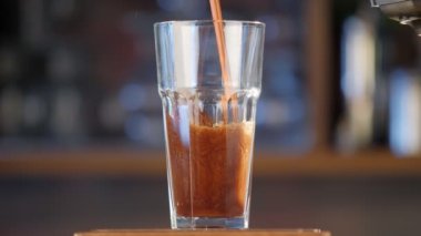 Barın üzerine şeffaf bir bardağa bira dök. Barın arka planındaki bir bardağa koyu bir bira dökülüyor. Kapat..