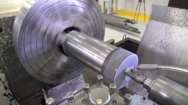 Torna tezgahı kullanarak metal bir atölyeyi delmek. Torna makinesi, metal şaft parçalarını kesiyor. Makineyi döndürerek metal işleme süreci.