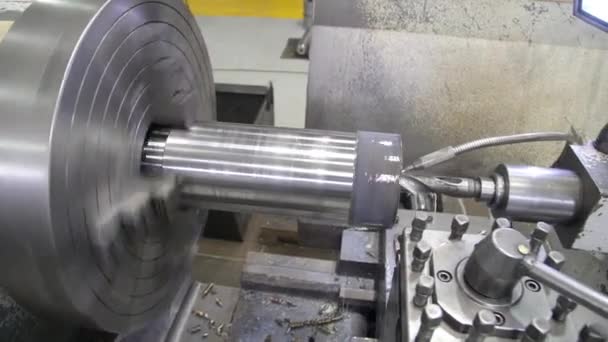 Torna tezgahı kullanarak metal bir atölyeyi delmek. Torna makinesi, metal şaft parçalarını kesiyor. Makineyi döndürerek metal işleme süreci. Stok Video