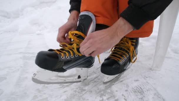 Erkekler patenlerin bağcıklarını sıkıyor. Parlak sarı bağcıklı hokey patenleri. Karla kaplı buz üzerinde kayak yapmaya hazırlanıyorum.. Stok Video