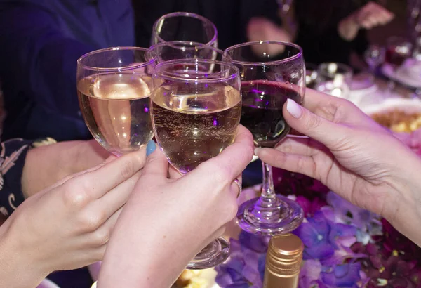 Glazen witte wijn in de handen van vrouwen. Kerstmis, Nieuwjaar, Vrijdag, vrienden ontmoeten — Stockfoto