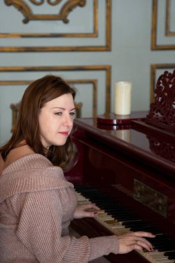 Bir kadın eski bir piyano çalar. Avrupa görünümlü esmer ve piyano