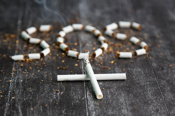 the ash and cigarette look like a cross, an artistic concept for world no tobacco day. Sign SOS of tobacco. Health risks of nicotine. The cigarette kills. black and white dark photo
