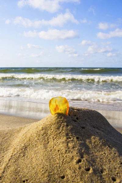 Ambra nella sabbia sullo sfondo delle onde del mare. — Foto Stock