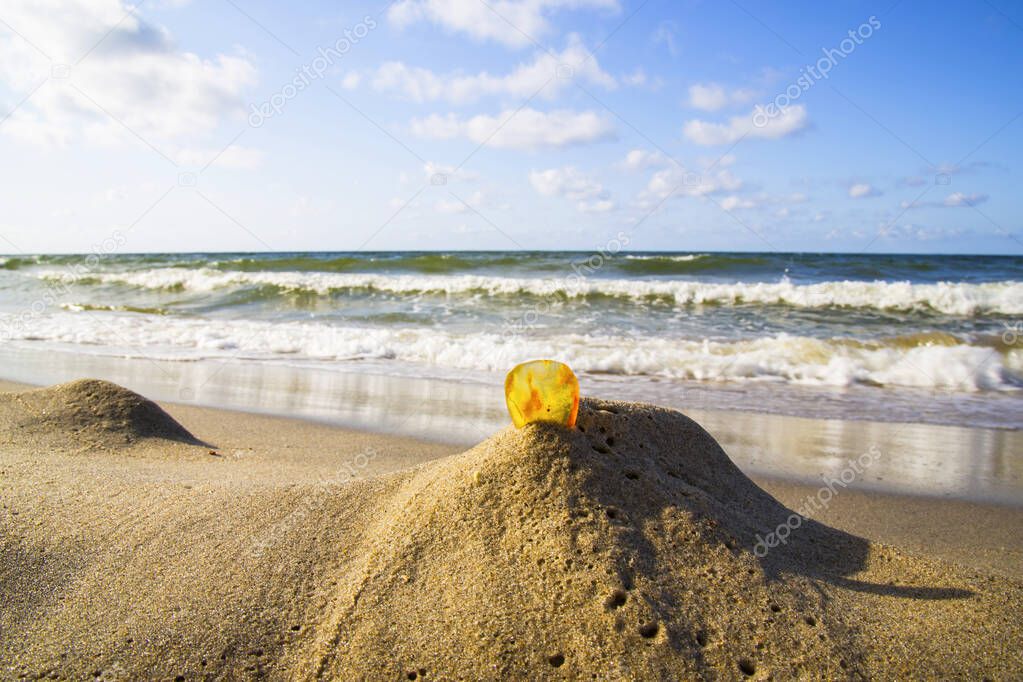 Amber in the sand against the background of sea waves.