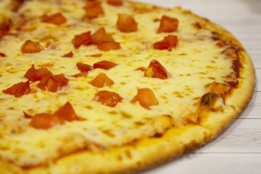 Peynirli ve domatesli pizza, İtalyan mutfağı, açık ahşap arka planda.