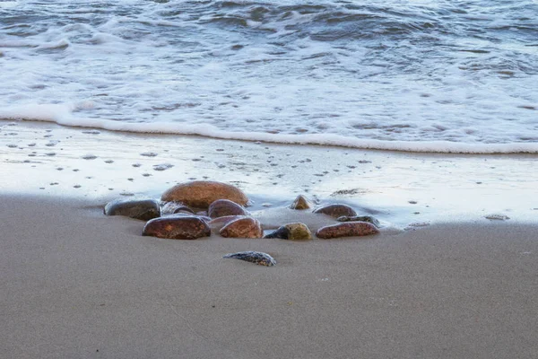 Kumlu sahilde deniz dalgaları ve kayalar. Denizde tatil, yüksek gelgit