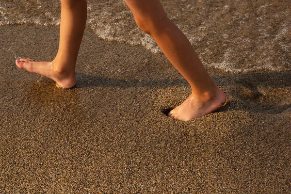 Beach trip-a woman walks on a sandy beach, leaving footprints in the sand. Close-up details of women\'s legs and Golden sand on the beach