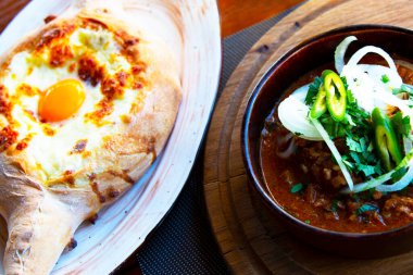 Kafkas mutfağı. Ajarian tarzında Khachapuri fırın ürünleri. Mozzarella ve yumurtalı açık turta. Gürcistan mutfağı, sokak yemekleri, ulusal abur cuburlar. Kafkas çorbası. Biftek soğanlı Solyanka.