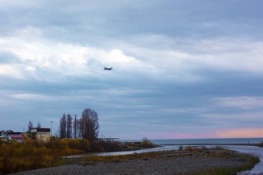 Nehir denize dökülür. Rusya 'nın Soçi Adler ilçesi Karadeniz' e akan Mzymta Nehri 'nin nehir yatağının manzarası. Dağ nehri gün batımında denize akıyor.