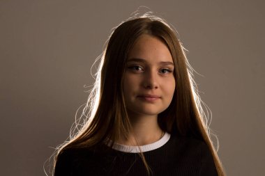 Stüdyoda uzun sarı saçlı güzel bir manken parıltılar ışığında poz veriyor, ışık saçlarına gölgeler çiziyor..