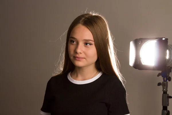 Ein schönes Model-Mädchen mit langen blonden Haaren posiert im Atelier im Licht der Blitze, das Konturlicht wirft Schatten auf ihr Haar. — Stockfoto