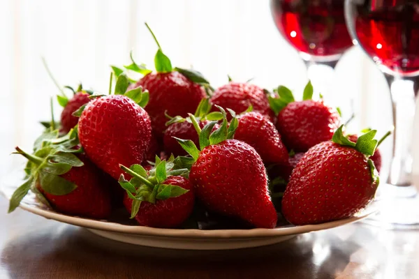 Vino hecho de bayas. Fresas frescas maduras y copas de vino tinto en el fondo — Foto de Stock