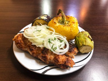 Beyaz tabakta ızgara et ve sebzeli Kafkas Luleh kebabı.