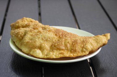 Büyük altın bir çeburek beyaz bir tabakta