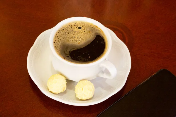 Cup White Coffee Candies Saucer Wooden Table Smartphone Nearby — Stock Photo, Image