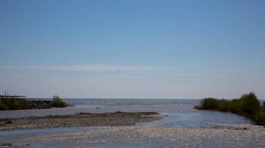 Nehir denize dökülür. Tatlı su ve tuzlu su buluşması. Konsept - her şey büyük olma eğilimindedir. Rusya, Adler, Mzymta Nehri Karadeniz 'e akar, yaz günü.