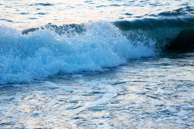 Baltık Denizi 'nin kumlu sahilinde köpüklü beyaz dalgalar. Mavi deniz ve parlak mavi gökyüzü, yüksek gelgit. Sahilde yaz