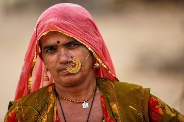 Rohet, Hindistan - 24 Şubat 2015: Bishnoi kabilesinin kimliği belirsiz kadını geleneksel kıyafet ve mücevherlerle evinin etrafında dolaşıyor