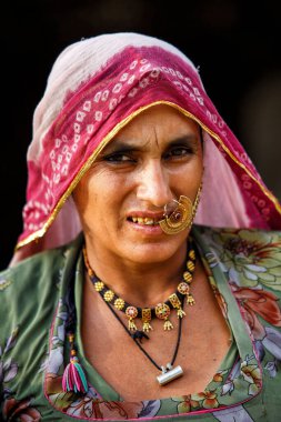 Rohet, Hindistan - 24 Şubat 2015: Bishnoi kabilesinin kimliği belirsiz kadını geleneksel kıyafet ve mücevherlerle evinin etrafında dolaşıyor