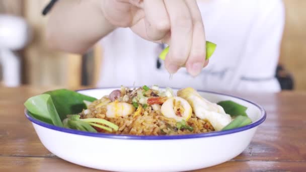 Femmina spremere acqua limone, lime, a frutti di mare gustosi freschi riso fritto con teste piccante da cibo delizioso in Thailandia, cibo tailandese — Video Stock